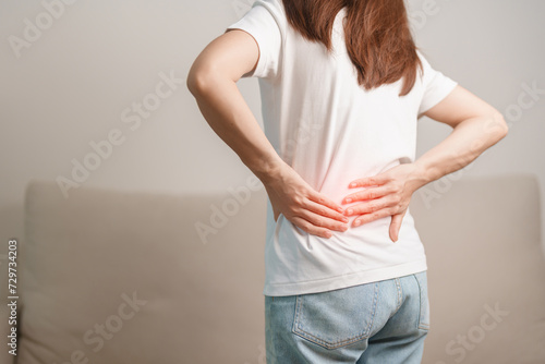 woman having back body ache during sitting on Couch at home. adult female with muscle pain due to Piriformis Syndrome, Low Back Pain and Spinal Compression. Office syndrome and medical concept