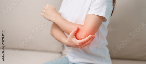 Quadro su tela Woman having elbow ache during sitting on couch at home, muscle pain due to lateral epicondylitis or tennis elbow