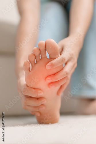 woman having barefoot pain during sitting on couch at home. Foot ache due to Plantar fasciitis and waking longtime. Health and medical concept photo