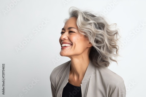 Portrait of a happy middle aged woman laughing against white background.