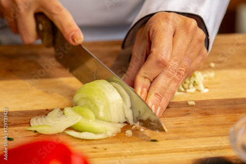 chef cortando cebola fresca na tábua de madeira preparando o tempero photo