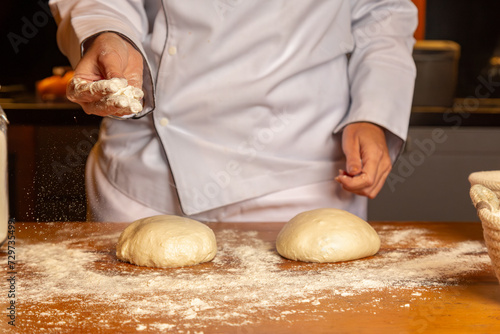 mão de chef jogando farinha e preparamdo a massa de pão artesanal  na cozinha photo