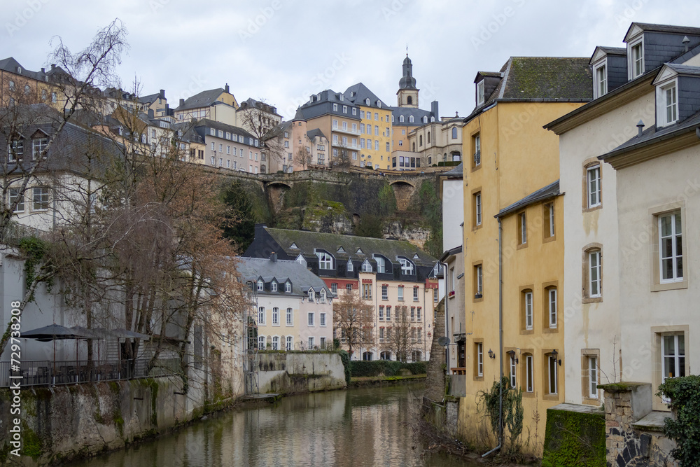 Colorful pink, yellow, and grey buildings in the old town village along a canal river reflection of Luxembourg City Europe