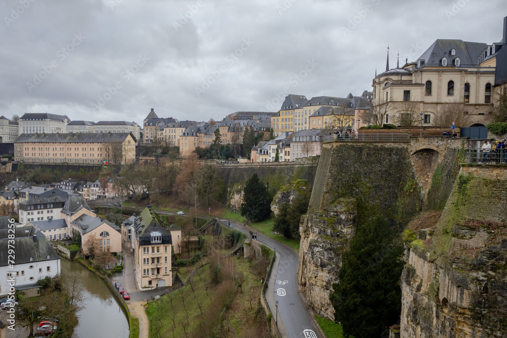 Church cathedral and colorful pink, yellow, and grey buildings in the old town village along a walled cliff and old bridge of Luxembourg City Europe