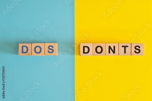 Obraz na płótnie Dos and Donts concept. Wooden blocks typography in bright blue and yellow background. w salonie