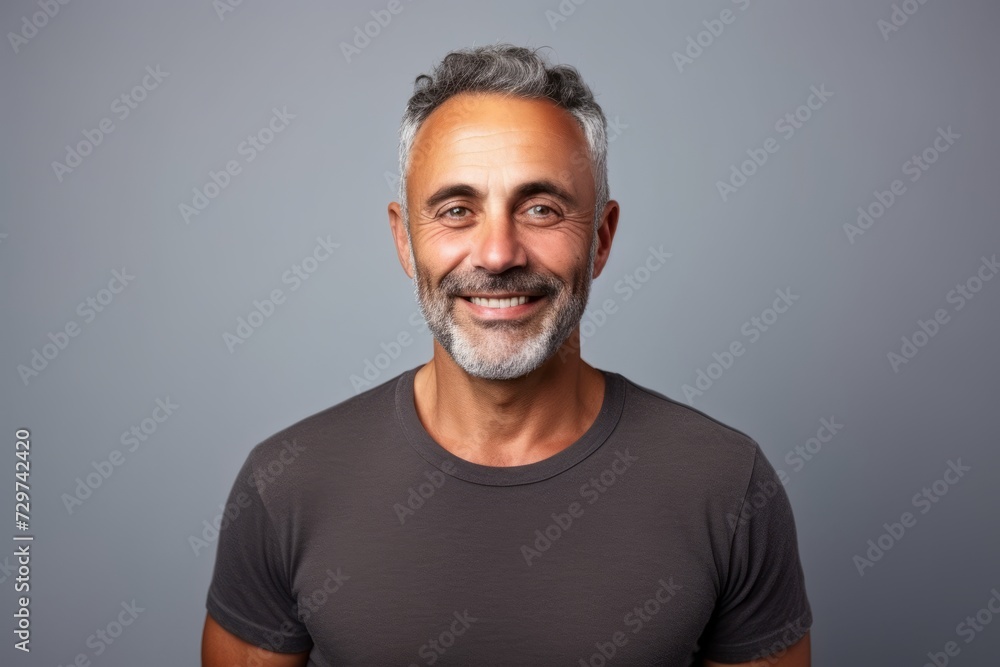 Handsome middle age man with grey hair and beard smiling at the camera on grey background Handsome middle age man with grey hair and beard smiling at the camera on grey background