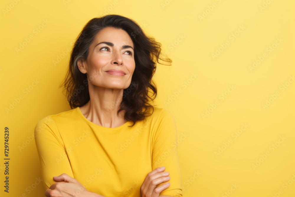 Portrait of a happy mature woman looking up over yellow background. Portrait of a happy mature woman looking up over yellow background.