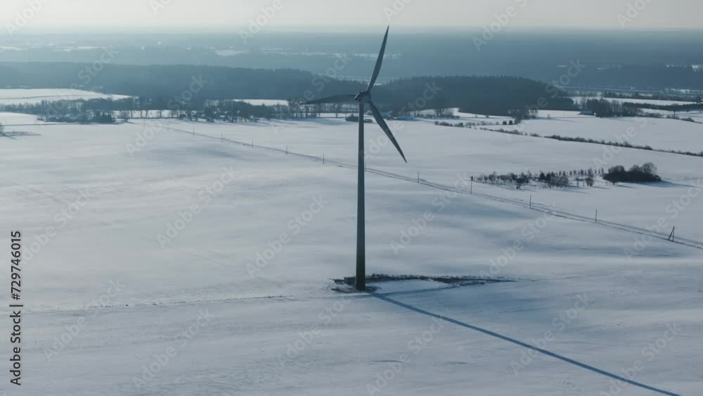 Drone encircles a solitary wind turbine amidst the snowy Baltic landscape Drone encircles a solitary wind turbine amidst the snowy Baltic landscape