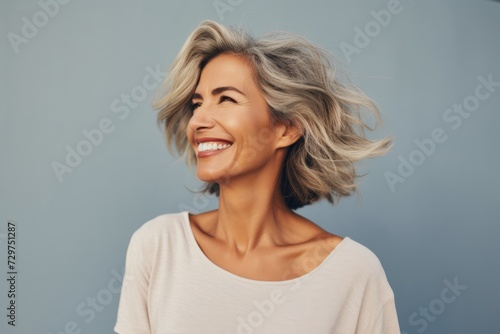 smiling middle aged woman with grey hair looking up over grey background