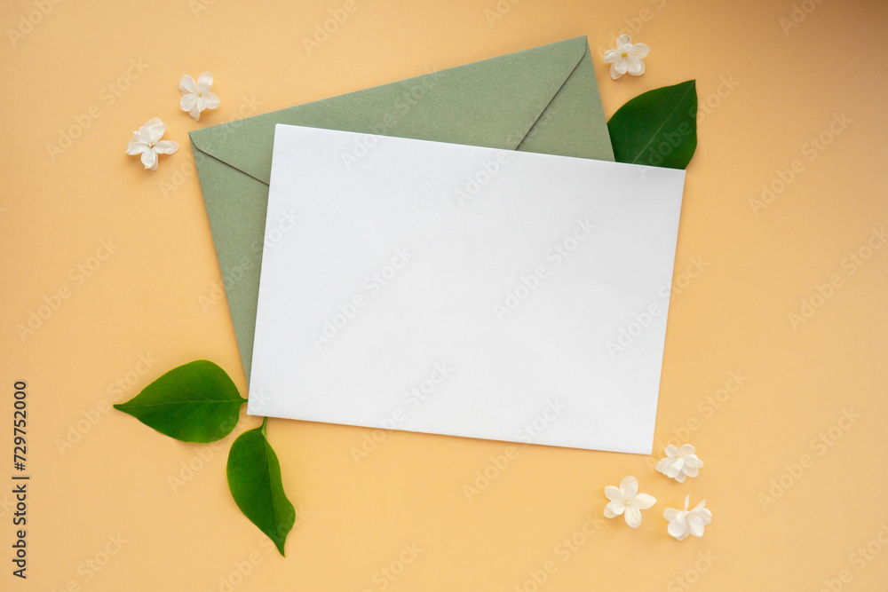 Composition with empty envelope and beautiful spring lilac flowers on beige background. Mockup card invitation greeting card postcard copy space template. Branches of lilac blooming bouquet. Composition with empty envelope and beautiful spring lilac flowers on beige background. Mockup card invitation greeting card postcard copy space template. Branches of lilac blooming bouquet.