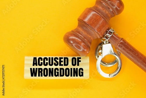 judge's hammer, iron handcuffs and sticks with the words accused of wrongdoing. the concept of accusation of wrongdoing. photo