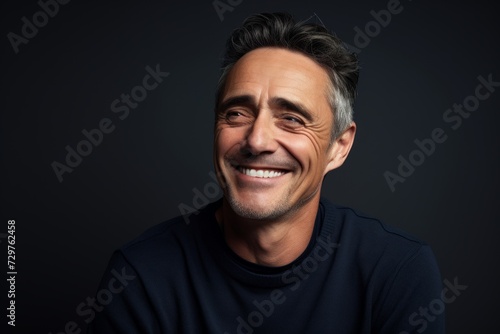 Portrait of a handsome middle-aged man laughing against a dark background. © Chacmool