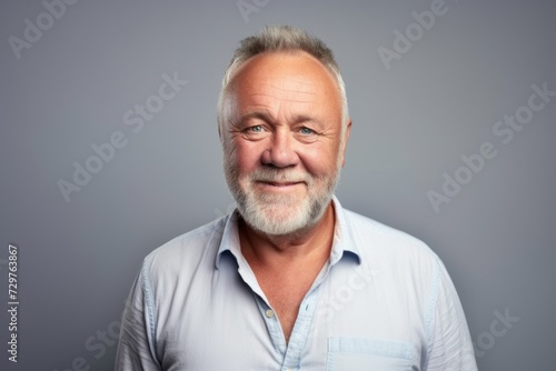 Portrait of a senior man in a shirt on a gray background.