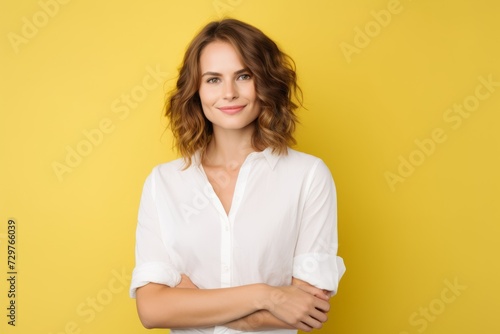Portrait of a beautiful smiling woman in white shirt on yellow background
