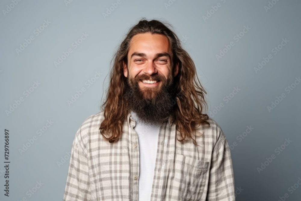 Portrait of a handsome man with long hair and beard smiling on grey background Portrait of a handsome man with long hair and beard smiling on grey background