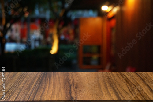 Empty dark wooden table in front of abstract blurred boken bankground of restaurant. Can used for display or montage your products. Mock up for space. photo