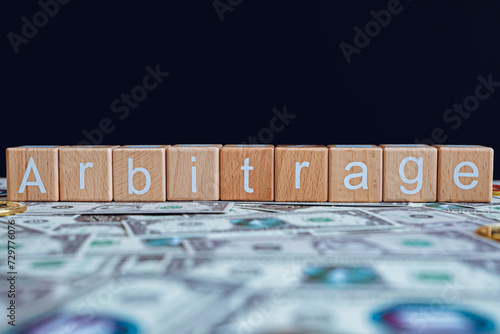 Foto Wooden blocks with the text Arbitrage on a black background and crypto banknotes scattered on the ground