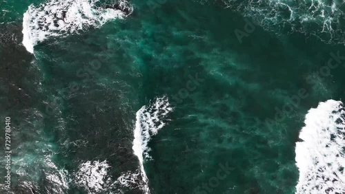 drone pull up shot of large and powerful waves crashing down on the surfers trying to catch the waves. photo