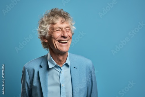 Portrait of a happy senior man laughing and looking at camera against blue background © Chacmool