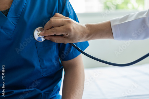 Male doctor caring for a patient holding a stethoscope listening to the patient during a home visit Doctor doing heart check examining man with heart disease, heart disease concept. Close-up image