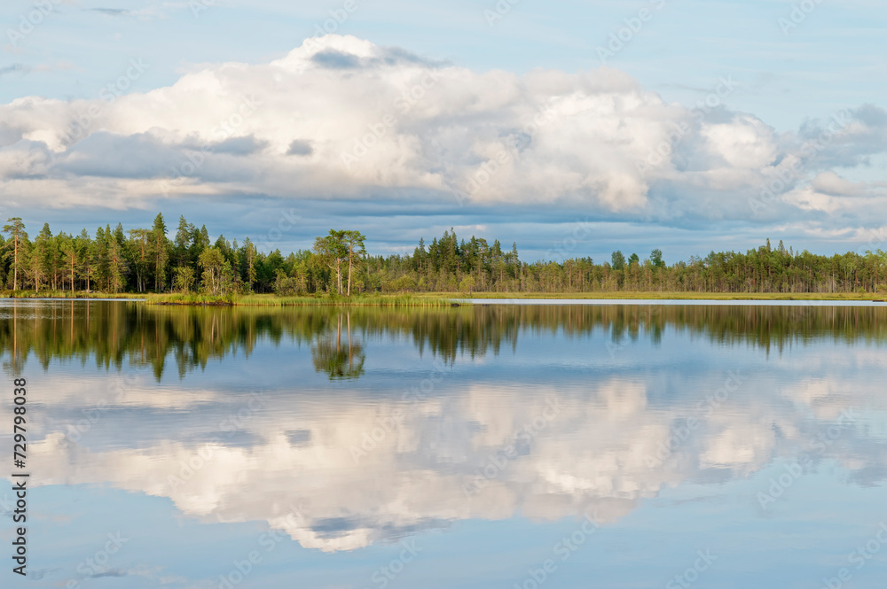 A tranquil partly cloudy summer evening by a lake with perfect reflection on the water surface, Northern Europe