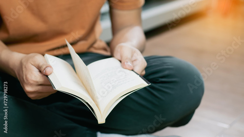 Student sitting on floor reading book in library