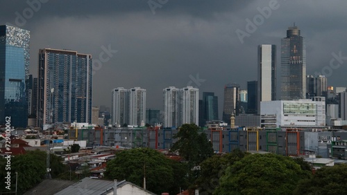 Image of tall buildings in a cloudy sky and trees