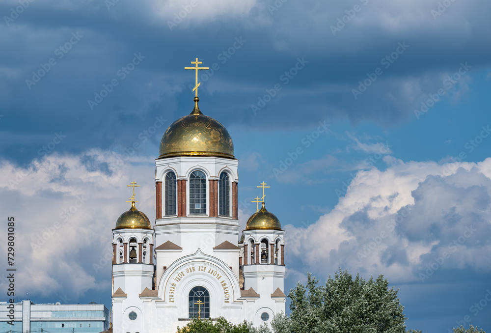 A church with golden domes against a sky with clouds.