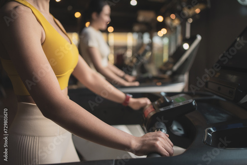 Two young woman are jogging on treadmill during her sports training in a gym.