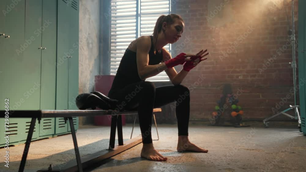 Focused young woman fighter boxer wraps hands wrists with boxing ...