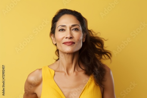 Portrait of a happy young woman with long curly hair on yellow background