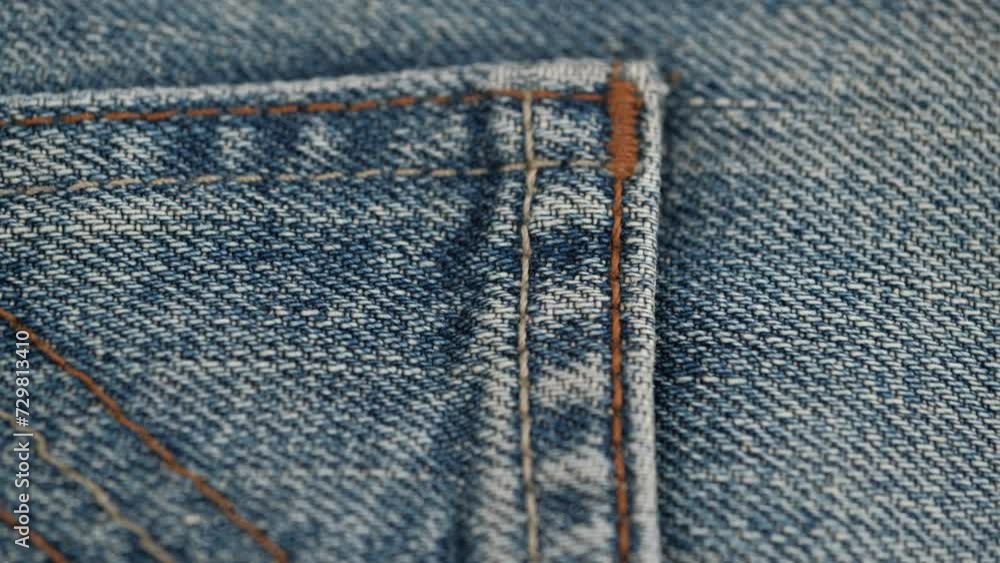 close up of rotation of jeans pocket with decorative stitching. background of blue jeans with decorative elements. concept of the garment industry and tailoring. close up of rotation of jeans pocket with decorative stitching. background of blue jeans with decorative elements. concept of the garment industry and tailoring.