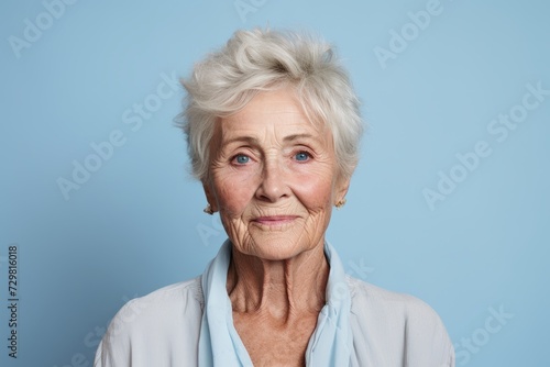 Portrait of a beautiful senior woman with grey hair on blue background © Inigo