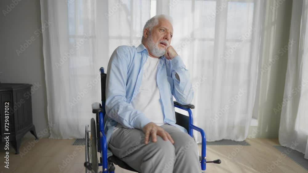 Old man in wheelchair looks at window. Thoughtful gray haired senior male at home enjoying pastime leisure. Living with physical legs trauma paralysis, sadness, loneliness of older people concept. Old man in wheelchair looks at window. Thoughtful gray haired senior male at home enjoying pastime leisure. Living with physical legs trauma paralysis, sadness, loneliness of older people concept.