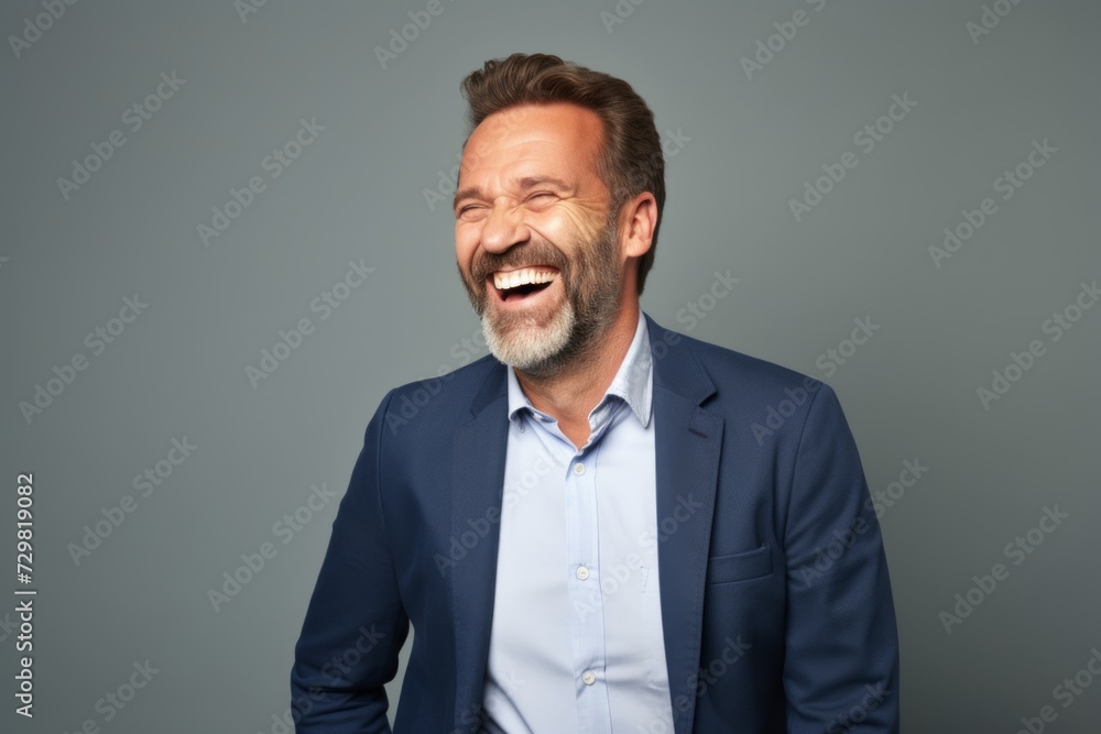 Handsome middle aged man laughing and looking at camera while standing against grey background Handsome middle aged man laughing and looking at camera while standing against grey background