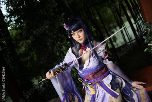 Portrait of a beautiful young woman game cosplay with samurai dress costume on Japanese garden