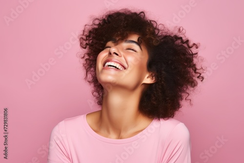 Portrait of a happy african american woman with curly hair on pink background