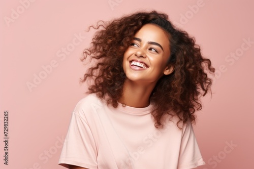 Happy young african american woman with long curly hair over pink background