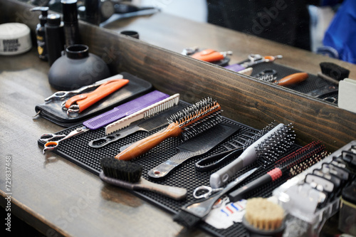 Close up view of hairdresser's tools. Cropped photo of barber's equipment on wooden table. Different combs and brushes lying on background of mirror.