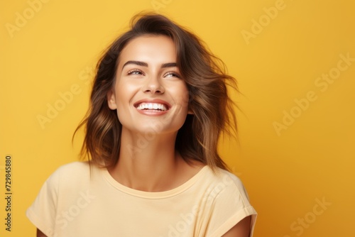 Young happy smiling woman in yellow t-shirt, over yellow background