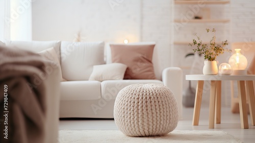 Cozy and stylish living room with white sofa, knitted pouf, and terra cotta accents. Scandinavian, hygge-inspired interior design with natural light and warm colors.