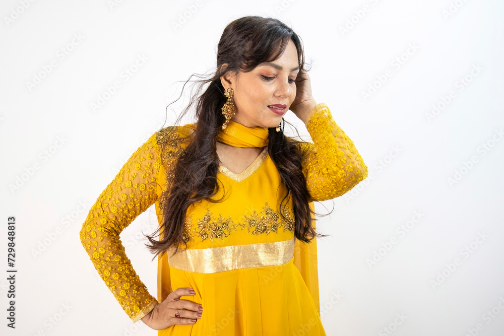 Indian woman posing in a vibrant yellow Anarkali suit, adorned with embroidery. Indian woman posing in a vibrant yellow Anarkali suit, adorned with embroidery.