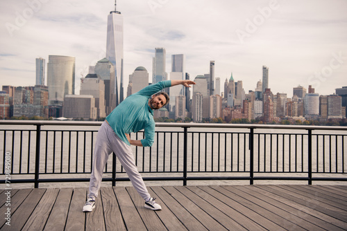 Man in fitness wear workout near Manhattan. Healthy fitness lifestyle. Active senior man is fitness exercising outdoor. Fitness after retirement. Mature retired sportsman doing stretching exercises.