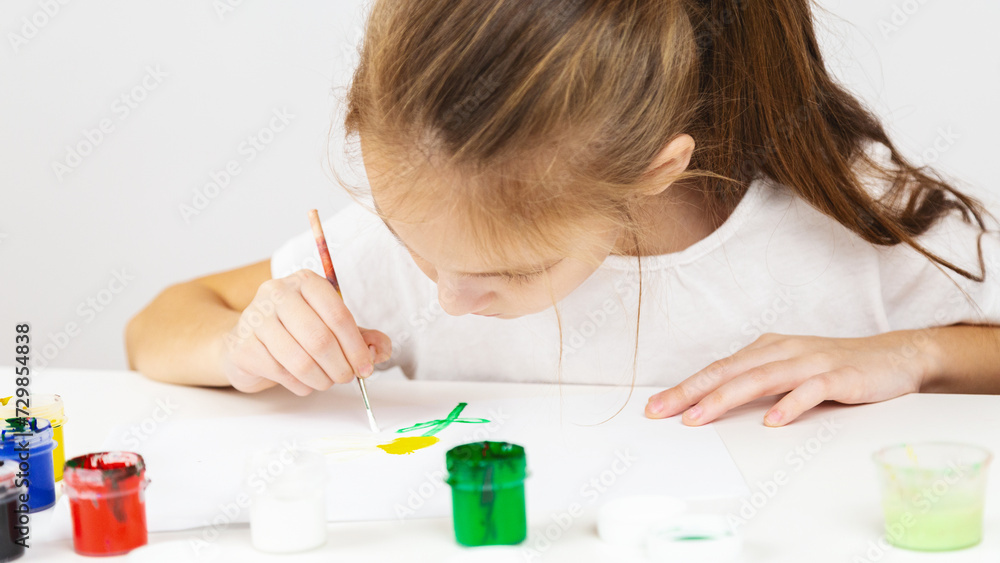 Portrait of a girl painting during an art class on at table indoors, additional drawing courses. Portrait of a girl painting during an art class on at table indoors, additional drawing courses.