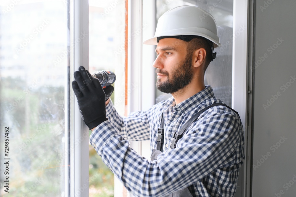 Construction worker installing window in house. Construction worker installing window in house.