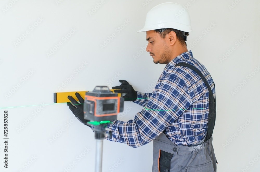 An Indian worker works in an empty apartment. A man in a uniform makes repairs inside the building An Indian worker works in an empty apartment. A man in a uniform makes repairs inside the building