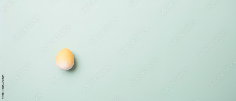 A yellow and white Easter egg isolated on a pale green background. A yellow and white Easter egg isolated on a pale green background.