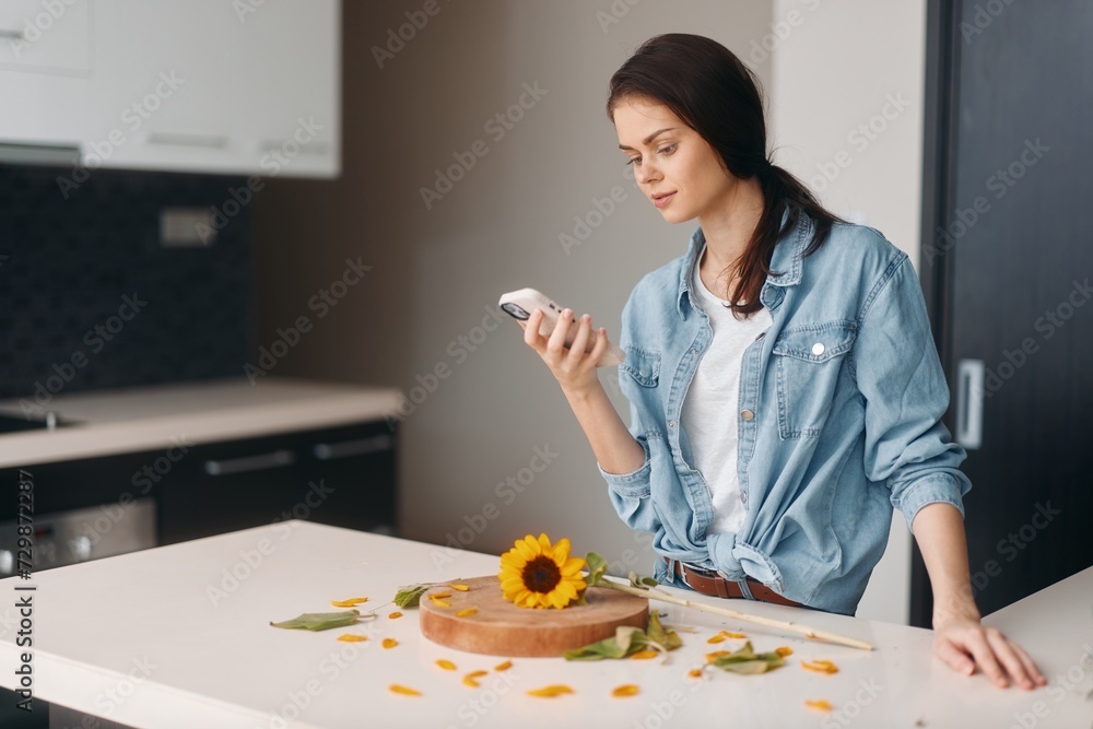 Beautiful young woman sitting at the kitchen table, holding a mobile phone and enjoying a healthy breakfast Beautiful young woman sitting at the kitchen table, holding a mobile phone and enjoying a healthy breakfast
