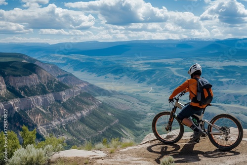 rider taking a break, bike propped against overlook with valley view