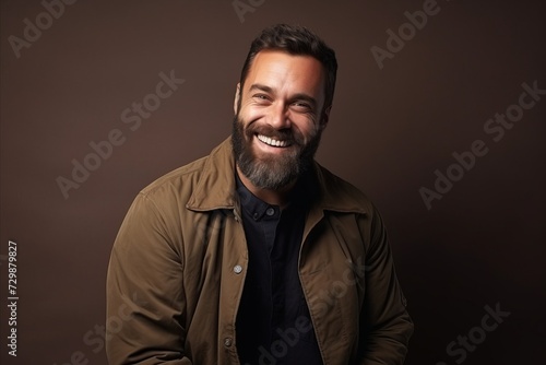 Portrait of a handsome bearded man in a brown jacket. Studio shot.